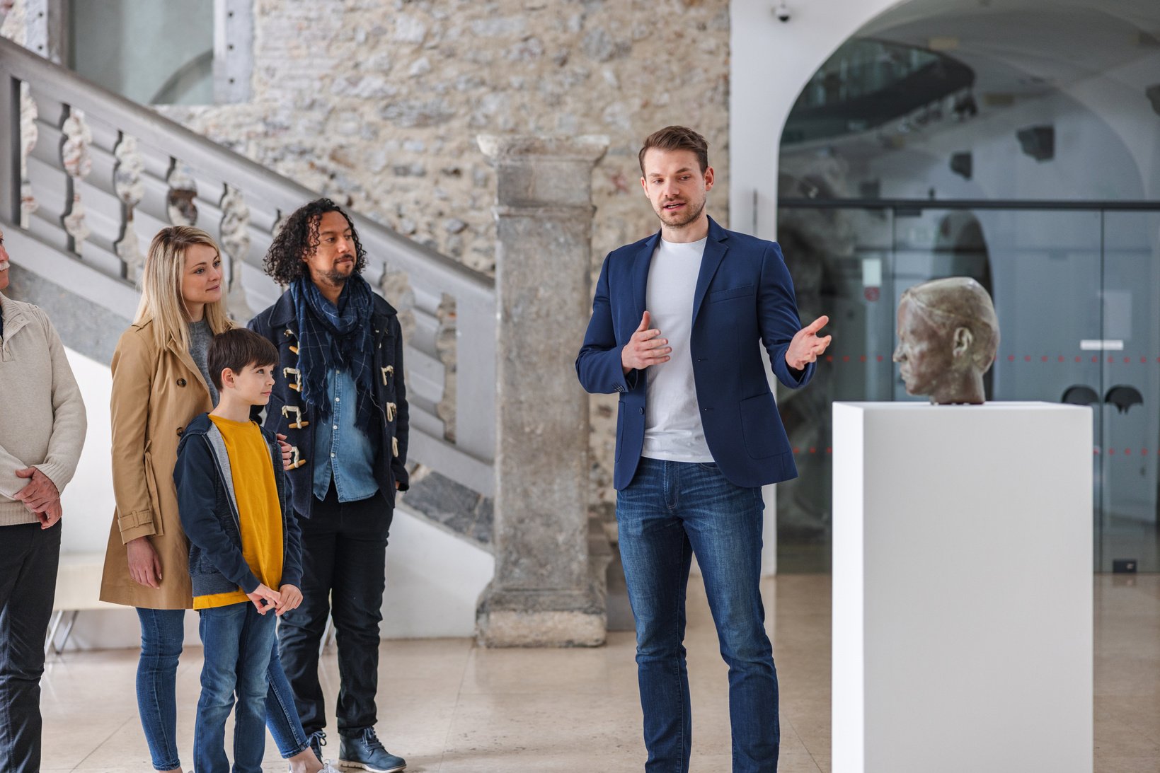 Adult Caucasian Male Museum Tour Guide Giving A Tour Of The Museum To A Diverse Group Of People